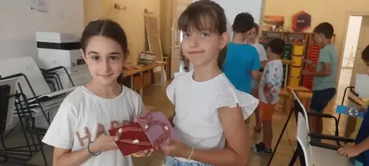 Две момичета показват украсено глинено сърце