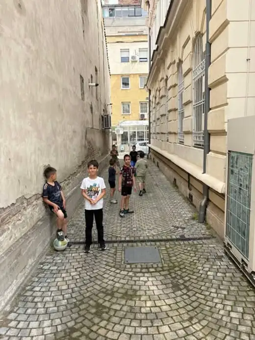 Момче с футболна топка в тясна улица между сградите