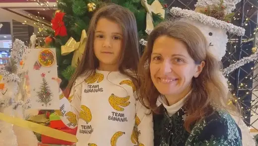 Две деца показват готовите си пана над маса с розова покривка и материали.