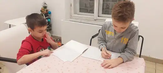 Момче в жълта блуза се държи за главата, докато решава задачи върху лист.